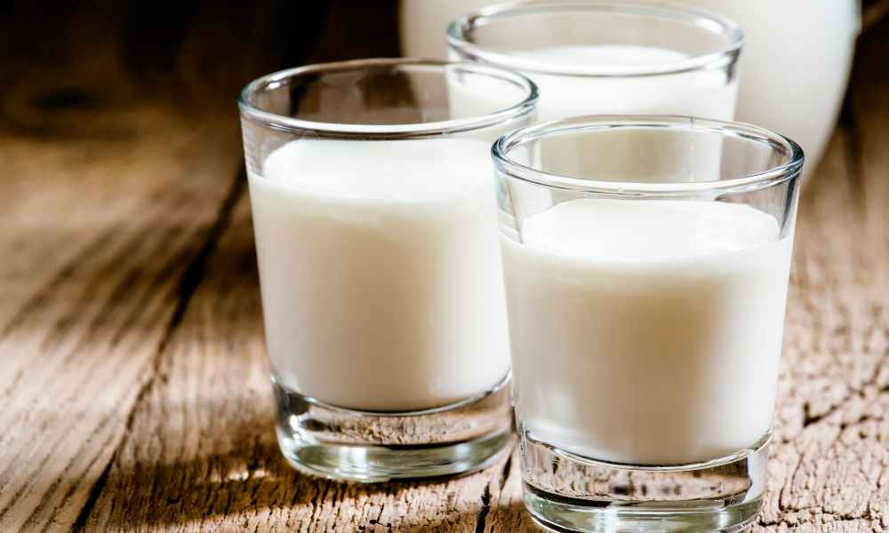 Three glasses of Australian goat milk on timber table
