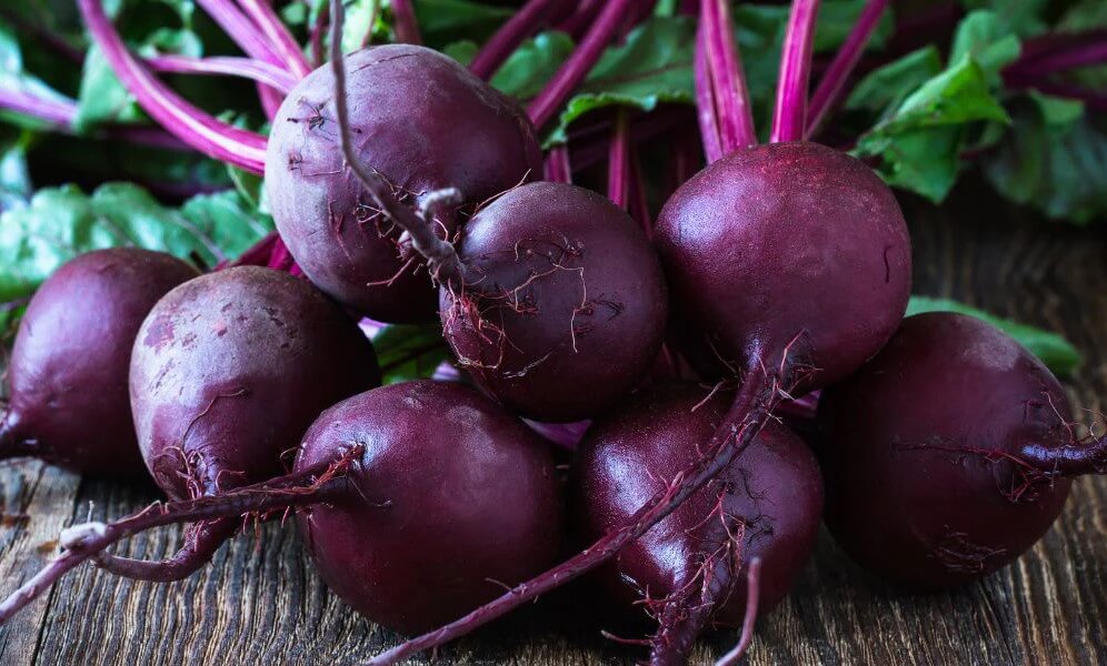 Whole fresh beetroots sitting on a timber table